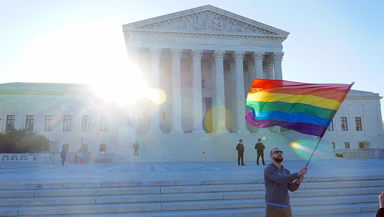 Man waves gay pride flag outside Supreme Court.